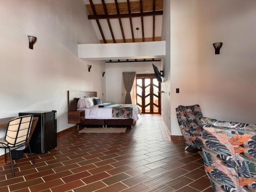 a bedroom with a bed and a couch and a chair at Hotel Cala in Cucaita