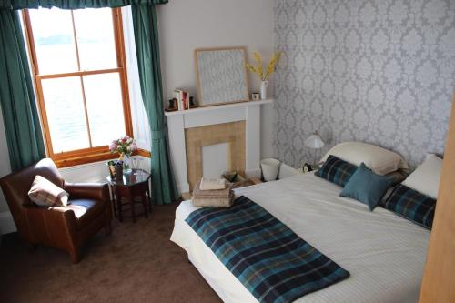 a bedroom with a bed and a chair and a fireplace at Alexandra Apartment - stunning view in Oban
