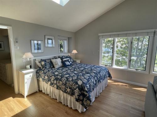 a bedroom with a bed with a blue comforter and two windows at Great Hill in Kennebunk