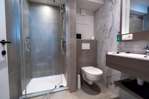 a bathroom with a shower and a toilet and a sink at The CORNR Seaview in Nieuwpoort
