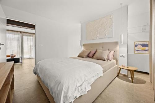 a white bedroom with a large bed and a table at Stillar Apartment near sea in Pula