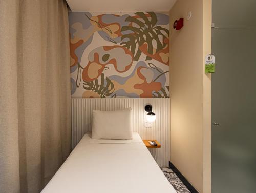 a bed in a room with a painting on the wall at B&B HOTEL Santos Dumont in Rio de Janeiro