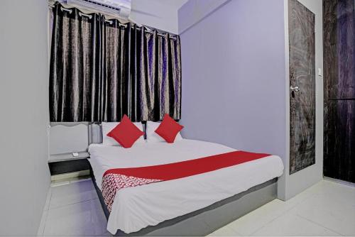 a bedroom with a bed with red pillows and a window at The Bull Group International in Surat