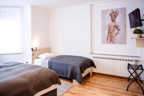 a bedroom with two beds and a picture on the wall at Rooms Ikar in Velika Gorica
