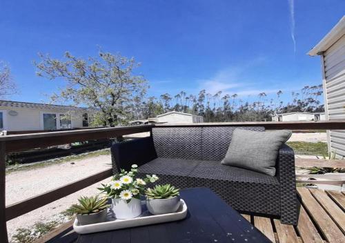 a wicker couch sitting on a deck with plants at Casa Nature's Avlis Bungalow 4XZ in Pataias
