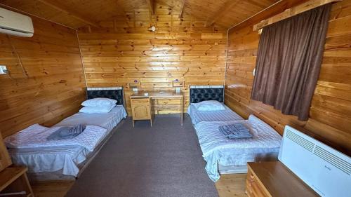 a room with two beds in a wooden cabin at Aydar Eco Yurt Camp in Ingichka