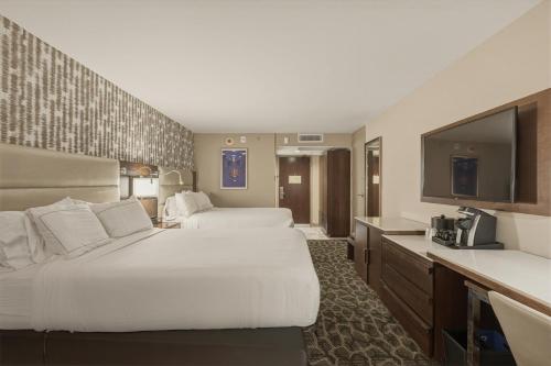 a hotel room with two beds and a flat screen tv at Grand Tuscany Hotel in Houston