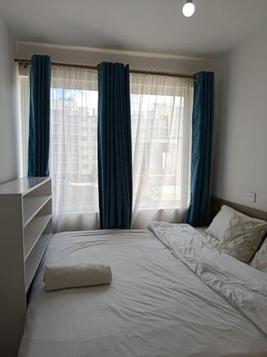 a bedroom with a bed with blue curtains and a window at HM Royal Homes in Nairobi