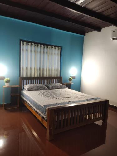 a bedroom with a wooden bed with a blue wall at 2 Bedroom Private Villa near the beach in Alleppey