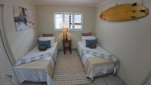 two twin beds in a room with a lamp at Ebb & Flow Beach House in Oyster Bay