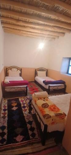 three beds in a room with a rug at ZAZA Guest house in Agoudal