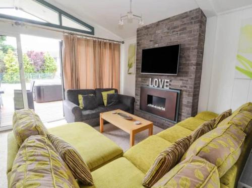 a living room with a couch and a fireplace at Honeysuckle lodge in Abergele