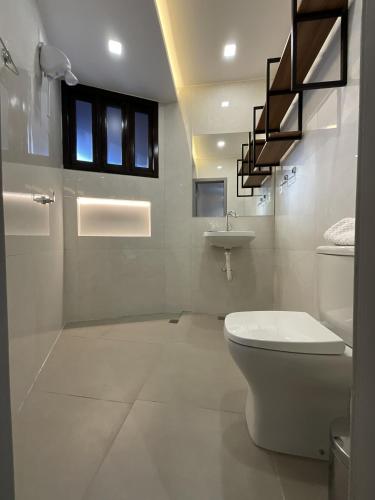 a white bathroom with a toilet and a sink at Studio moderno com ar condicionado central in Aracaju