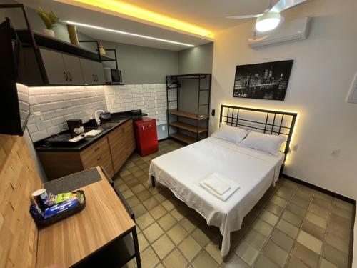 a small room with a bed and a kitchen at Studio moderno com ar condicionado central in Aracaju