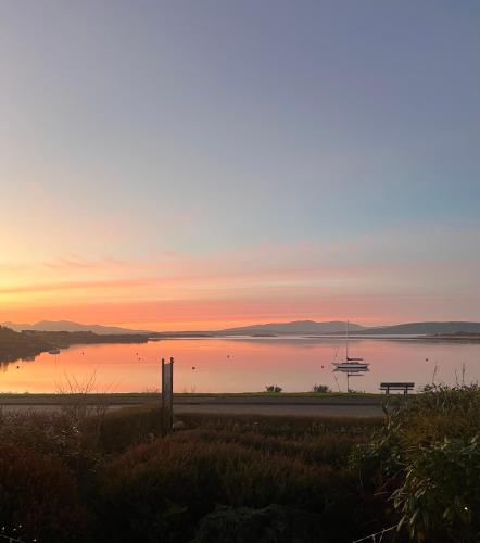 a sunset over a body of water with a bench at Ronebhal Guest House in Oban