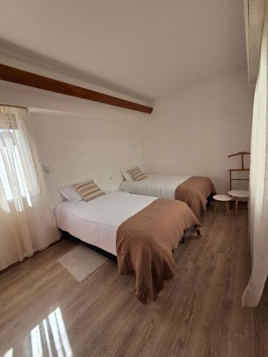 two beds in a room with wooden floors at Casa LIDIA Hostel in Comodoro Rivadavia