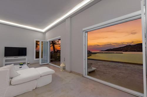 a living room with a white couch and large windows at Sunset Villa in Posidhonía