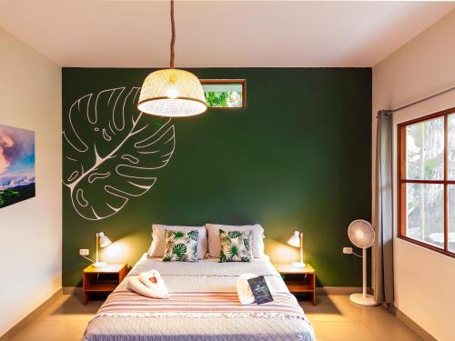 a bedroom with a green wall and a bed with pillows at Taki Tambo Lodge in Tarapoto
