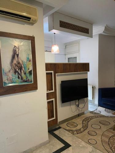 a living room with a television and a painting of a horse at Studio in Ariana