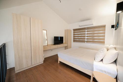a bedroom with a bed and a window and a television at Casita Benito Loft A in Sangley Point Naval Station