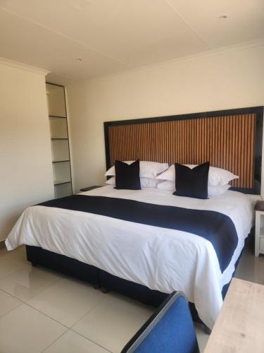 a bedroom with a large bed with a wooden headboard at The Pebbles-UA in Mahikeng