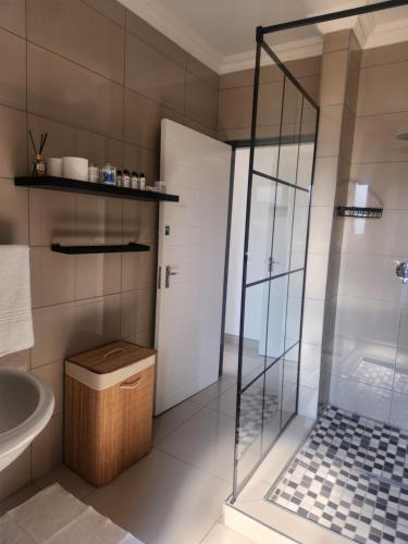 a bathroom with a glass shower and a sink at The Pebbles-UA in Mahikeng