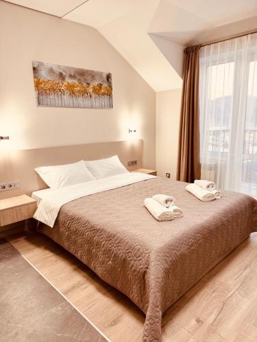 a bedroom with a large bed with two towels on it at Polyana Park House aparts in Polyana