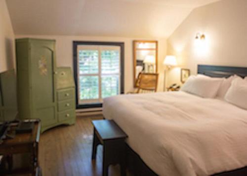 a bedroom with a bed and a dresser and a window at The Little Inn in Bayfield