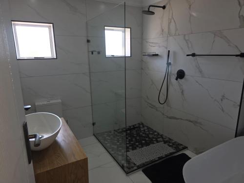 a bathroom with a glass shower and a sink at Heuwels Haven in Mossel Bay