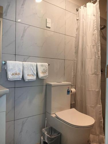 a bathroom with a toilet and towels on the wall at 2 double and 1 sofa beds Chalet D in Rotorua