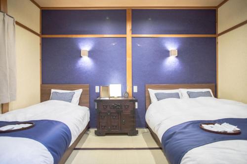 two beds in a room with blue walls at Nijojo Taiken Inn in Kyoto