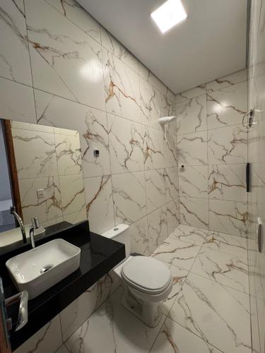 a bathroom with a white toilet and a sink at Pousada Serena - Alter do Chão in Santarém