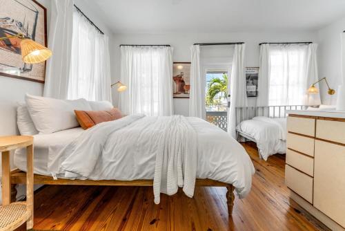 a bedroom with a large bed with white sheets and wood floors at NIGHTCAP @ Speakeasy Inn Key West! in Key West