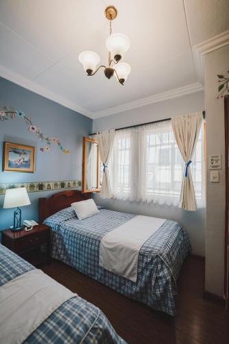 a bedroom with two beds and a chandelier at Hotel Posada del Angel in Cuenca