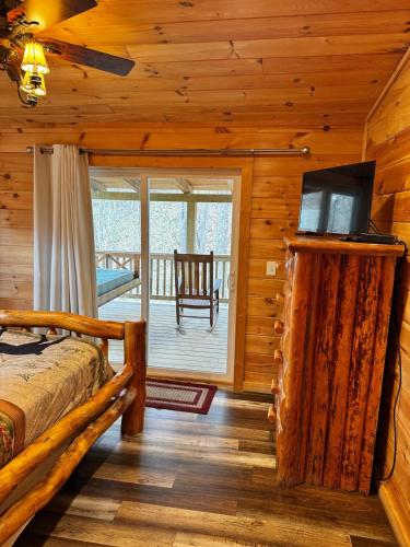 a log cabin bedroom with a bed and a balcony at Creekside Blessings Cabin in Beech Mountain