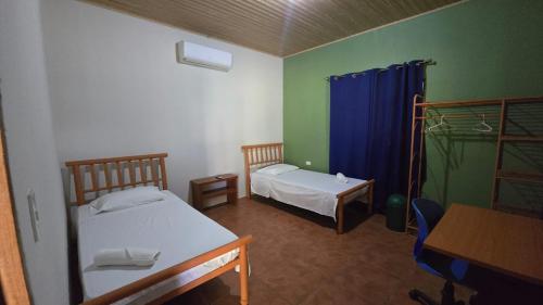 a room with two beds and a table and a desk at La Paloma Hostal in Moyogalpa