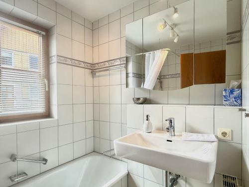 a bathroom with a sink and a tub and a mirror at Ferienwohnung Im schönen Dorf - idyllische Lage mit Terrasse und Garten in Lindau-Bodolz