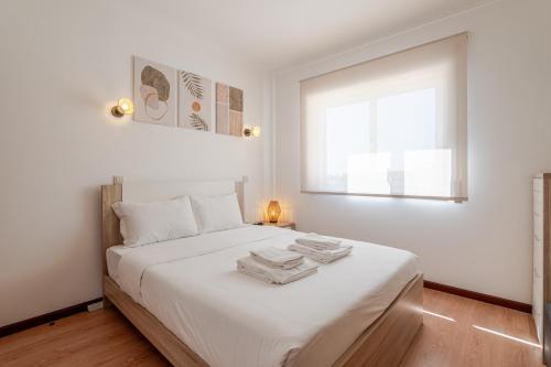 a bedroom with a bed with white sheets and a window at Sunset Terrace House by Destiny Houses in Esmoriz