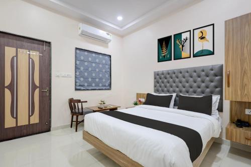 a bedroom with a large bed and a chair at Super HOTEL O MATRI CROWN in Raipur