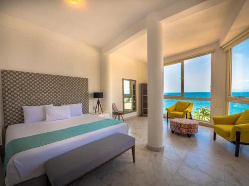 a bedroom with a bed and a view of the ocean at Marboka Hotel & Suites in Puerto Vallarta
