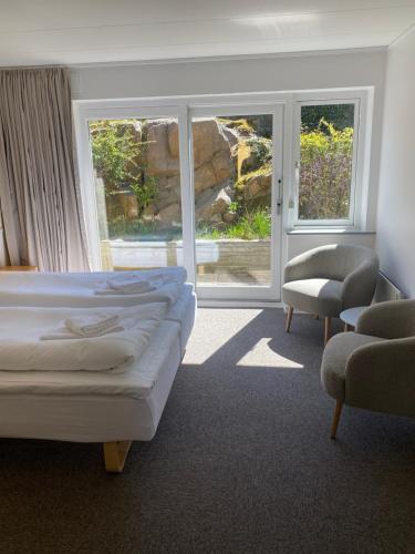 a bedroom with a bed and a chair and windows at Hotel Villum in Sandvig