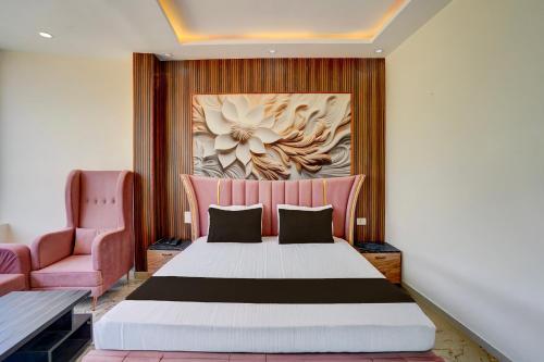 a bedroom with a bed and a pink chair at Hotel O J K Galaxy Hotel in Juhi Bari