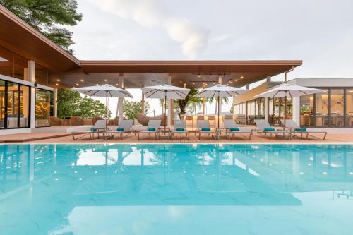 a pool at a hotel with chairs and umbrellas at LIV Hotel Phuket Patong Beachfront in Patong Beach