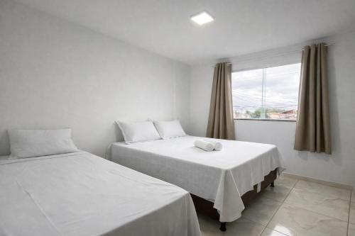two beds in a room with a window at Berenice Concept Residence - By Temporada Expert in Feira de Santana