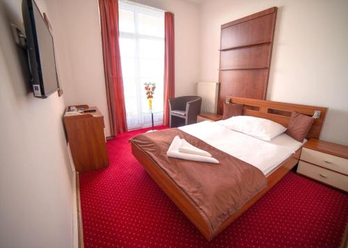 a bedroom with a bed with two white shoes on it at Hotel Palace in Nový Smokovec