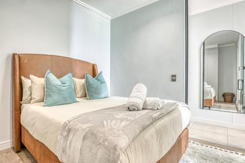 a bedroom with a bed with blue pillows and a mirror at Caica Executives at Ellipse 4103 in Midrand