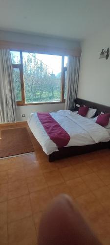 a bedroom with a large bed in front of a window at Peaceful huts in Manāli