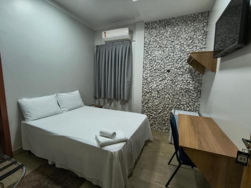 a bedroom with a bed and a desk and a window at Hotel do Porto in Porto Velho