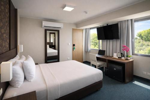 a hotel room with a large bed and a desk at Palmetto Hotel Business San Miguel in Lima