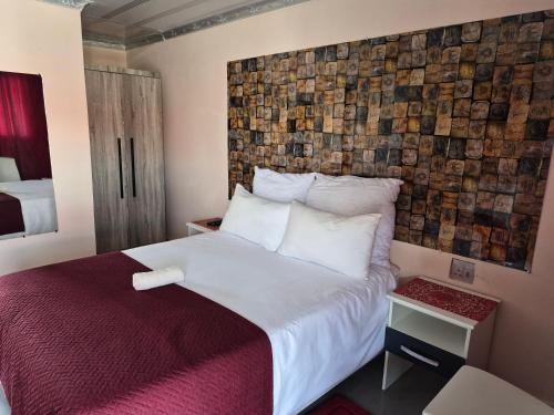 a hotel room with a large bed and a wall at Sweetwaters Guest House in Estcourt